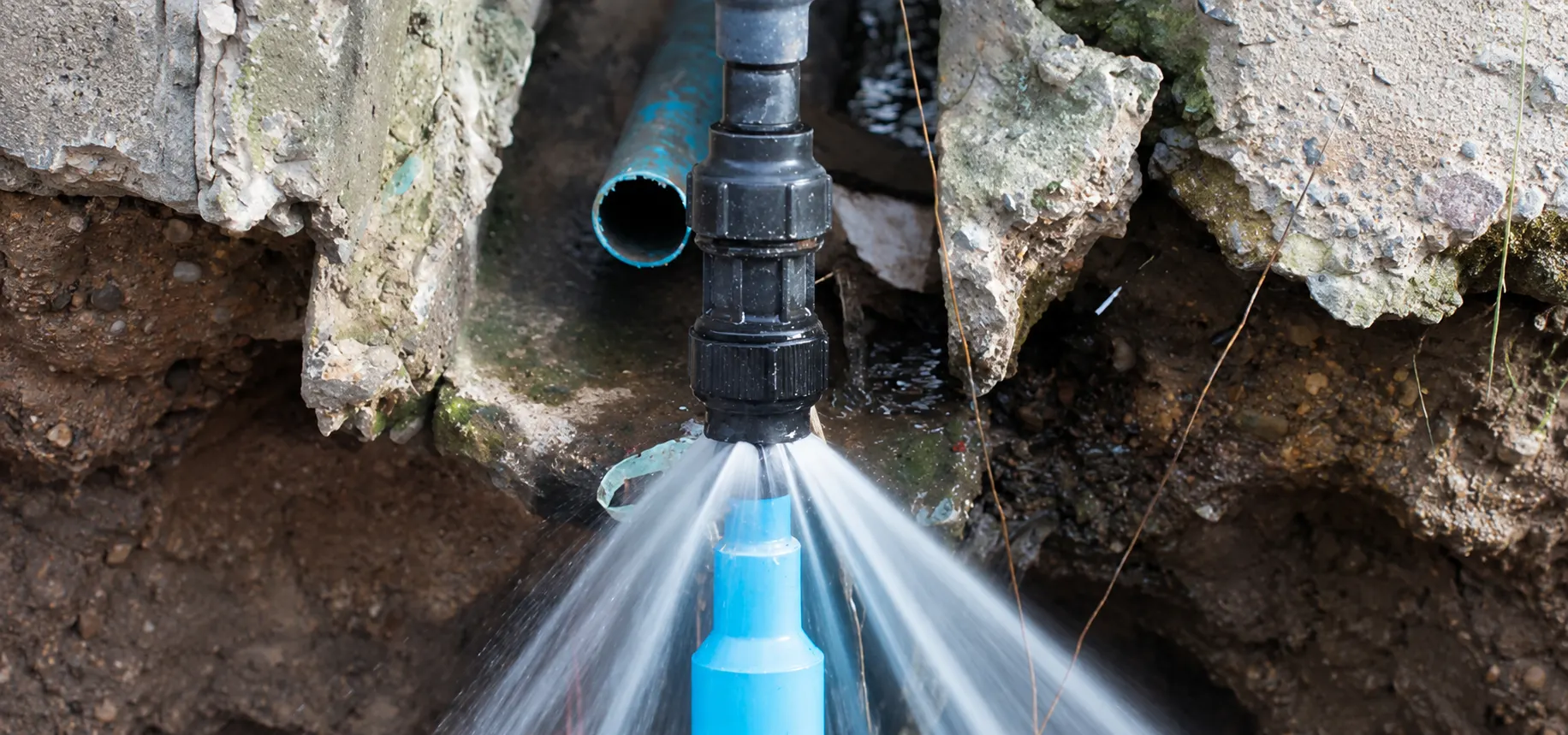 Water spraying from a cracked buried pipe in an excavated trench