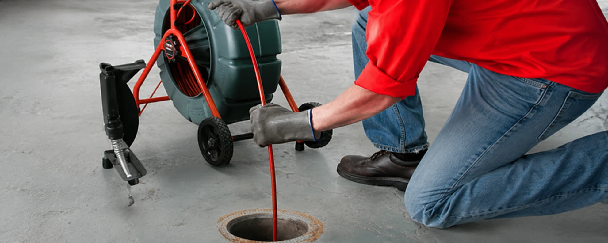 Technician operating a drain cleaning machine at a floor drain